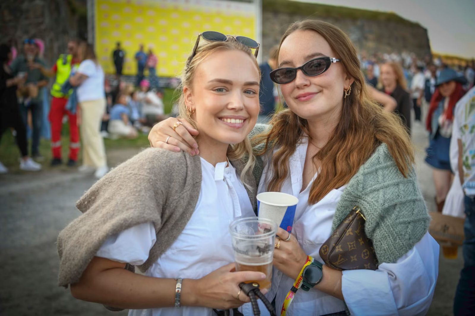 To venninner smiler med drikke på festivalområdet