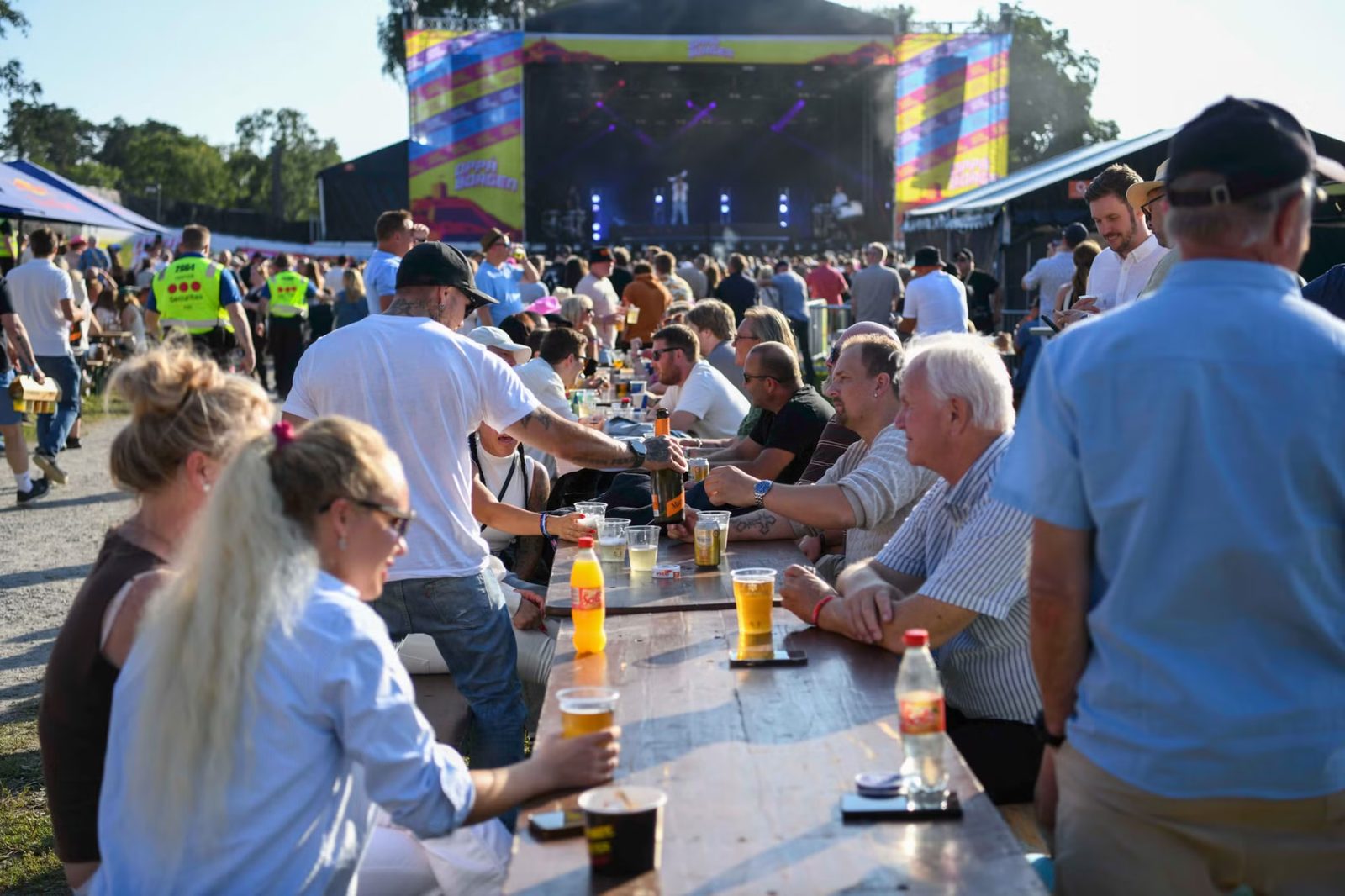 Festivalgjester ved langbord med scenen i bakgrunnen